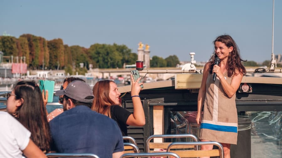 Une femme guide avec le sourire entrain de commanter une croisiere sur le toit d'une péniche à Paris
